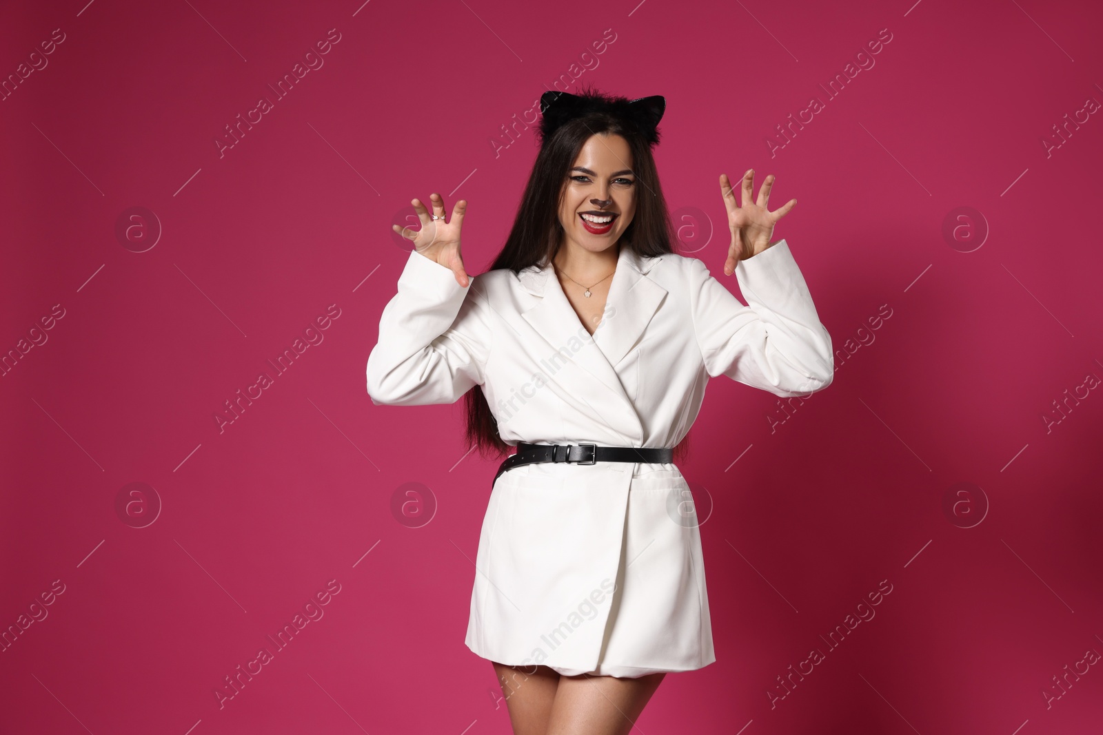 Photo of Playful woman with cat makeup and ears on pink background