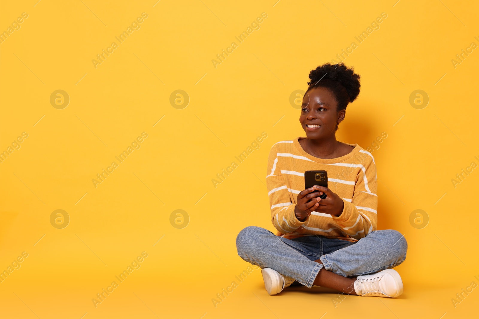 Photo of Happy woman with smartphone on yellow background. Space for text