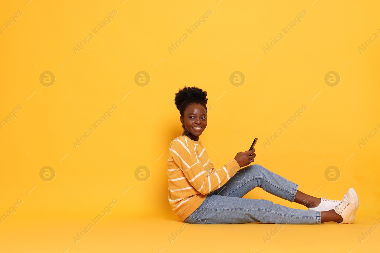 Photo of Happy woman with smartphone on yellow background. Space for text