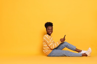 Photo of Happy woman with smartphone on yellow background. Space for text