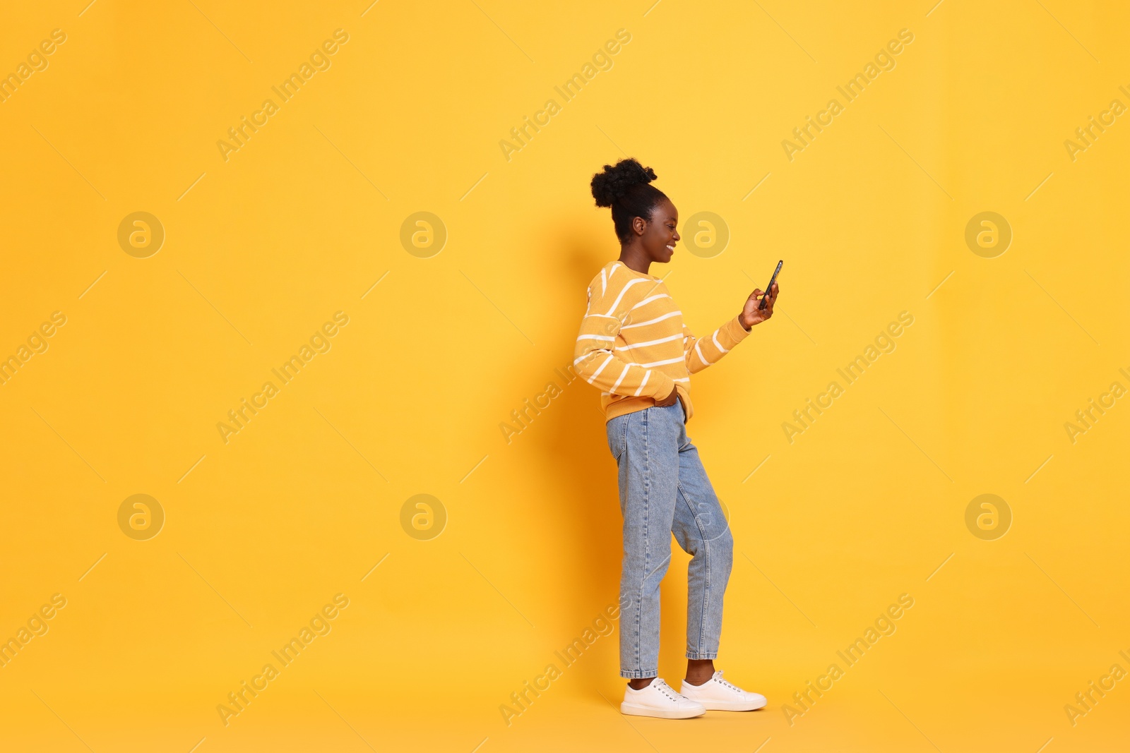 Photo of Happy woman with smartphone on yellow background. Space for text