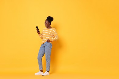 Photo of Happy woman with smartphone on yellow background. Space for text