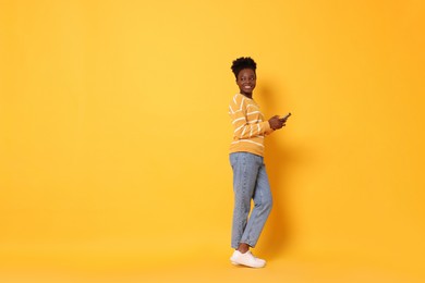 Photo of Happy woman with smartphone on yellow background. Space for text