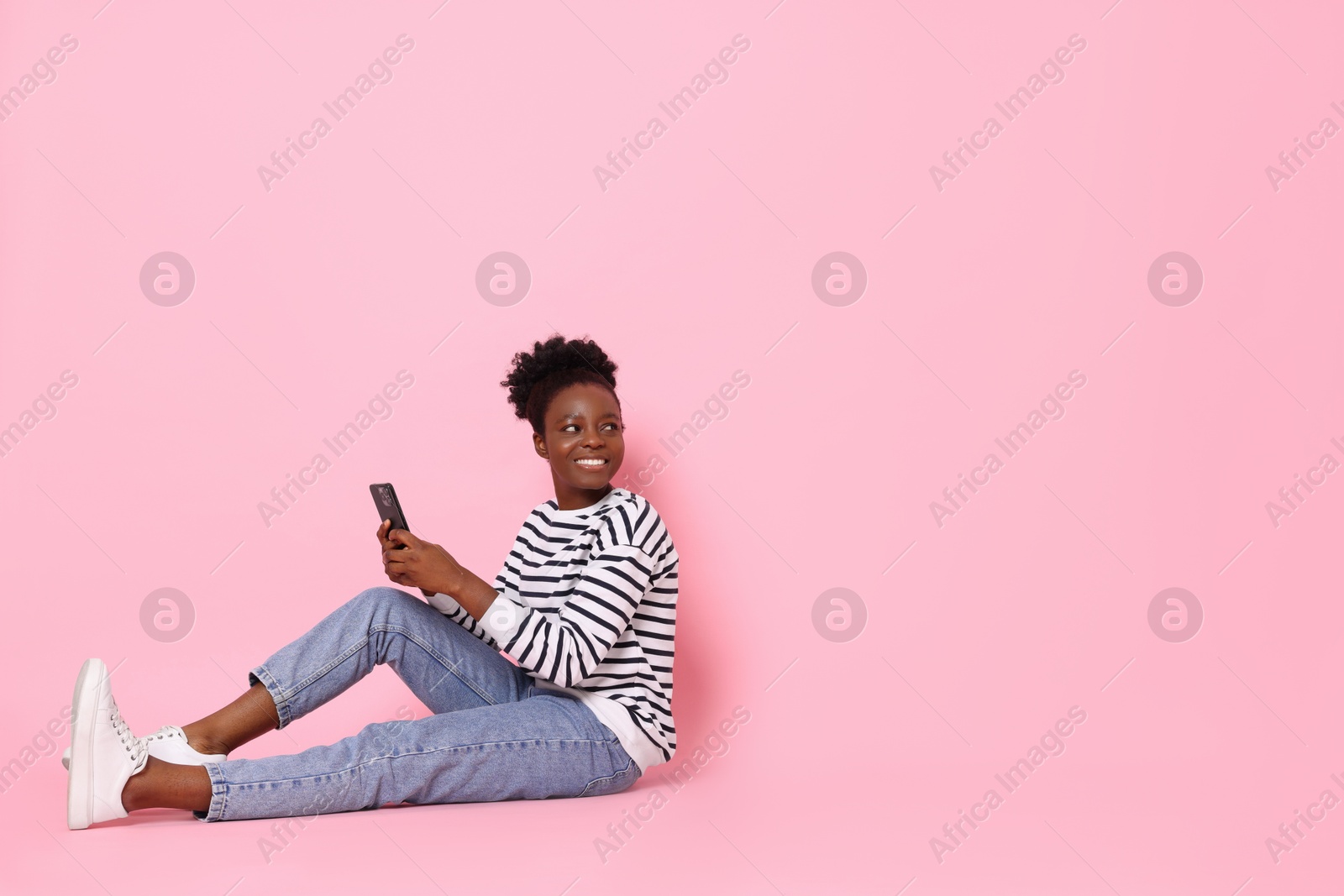 Photo of Happy woman with smartphone on pink background. Space for text