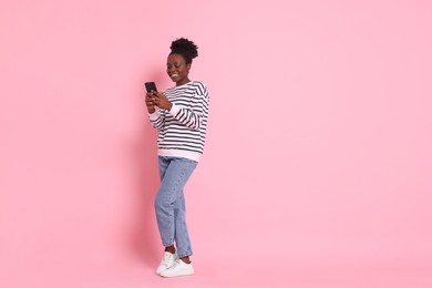 Photo of Happy woman with smartphone on pink background. Space for text