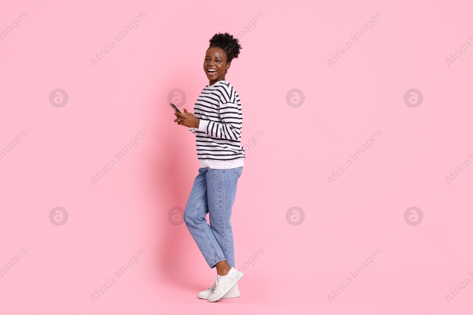 Photo of Happy woman with smartphone on pink background. Space for text