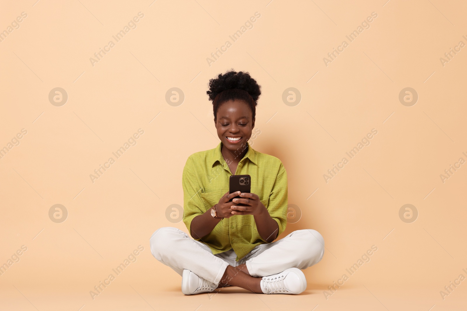 Photo of Happy woman with smartphone on beige background