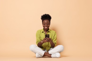 Photo of Happy woman with smartphone on beige background