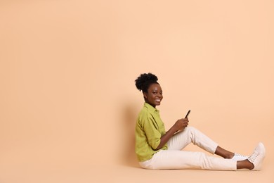 Photo of Happy woman with smartphone on beige background. Space for text