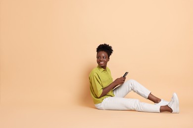 Photo of Happy woman with smartphone on beige background. Space for text