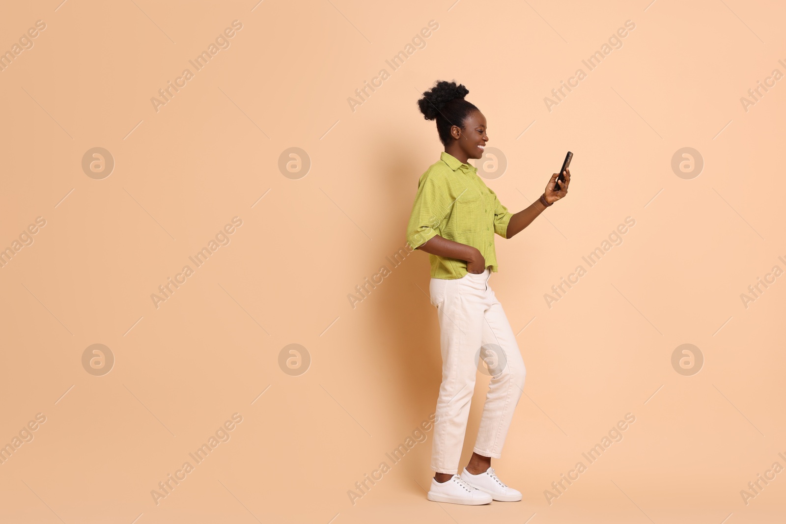 Photo of Happy woman with smartphone on beige background. Space for text