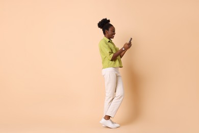 Photo of Happy woman with smartphone on beige background. Space for text