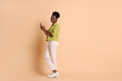 Photo of Happy woman with smartphone on beige background. Space for text