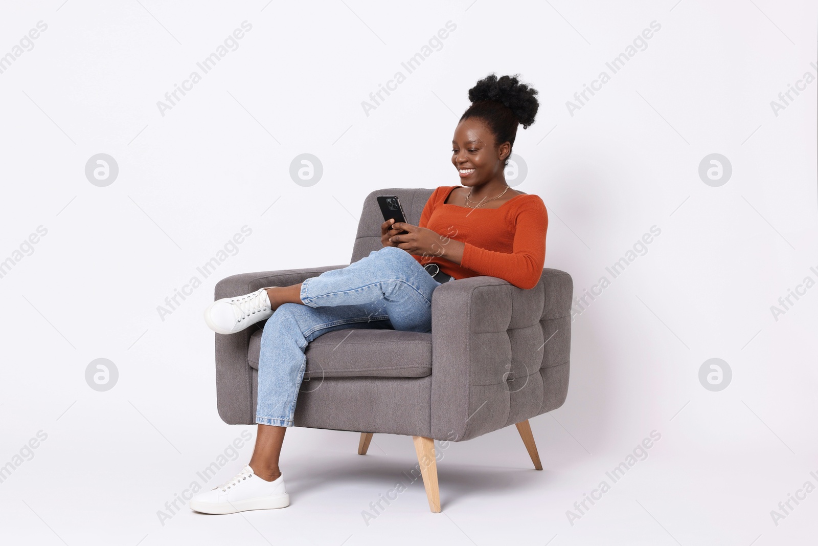 Photo of Smiling woman with smartphone sitting in armchair on white background