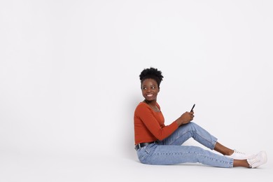 Happy woman with smartphone on white background. Space for text