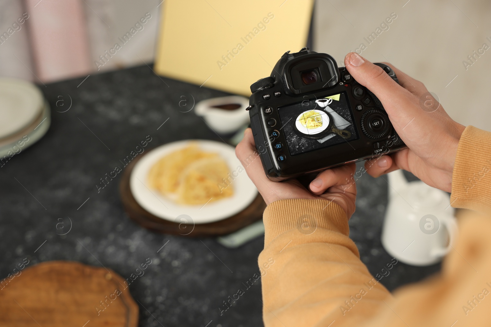 Photo of Man taking photo of crepes with professional camera in studio, closeup. Selective focus