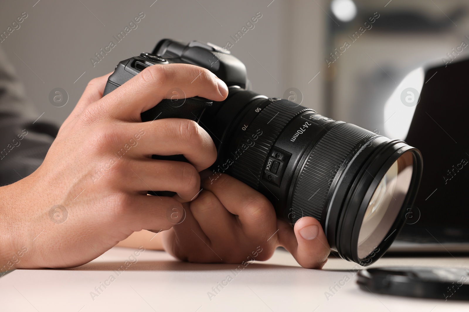 Photo of Photographer with professional camera at white desk indoors, closeup