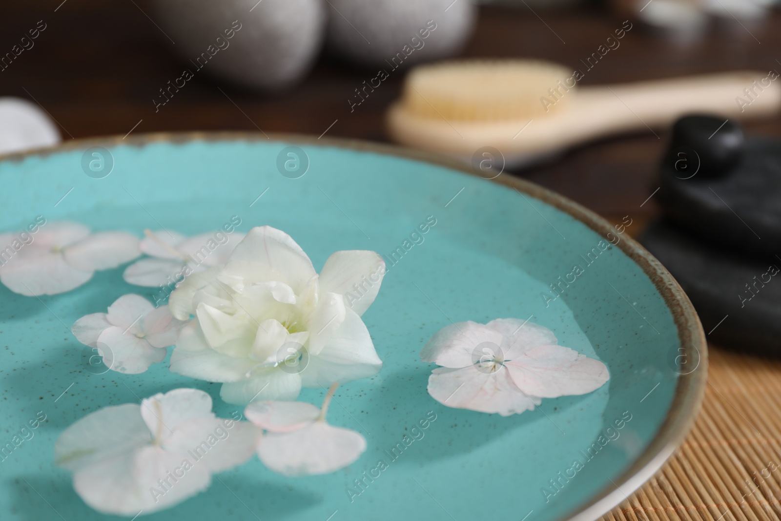 Photo of Bowl of water with flowers on table, closeup. Spa treatment