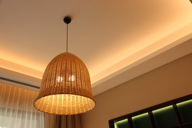 Photo of Stylish pendant lamp on ceiling indoors, low angle view