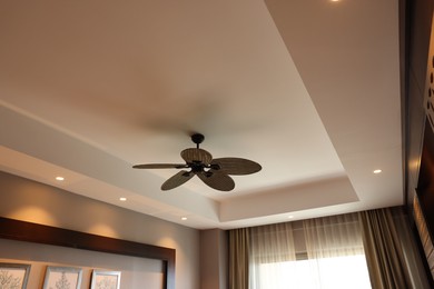 Photo of Modern ceiling fan indoors, low angle view