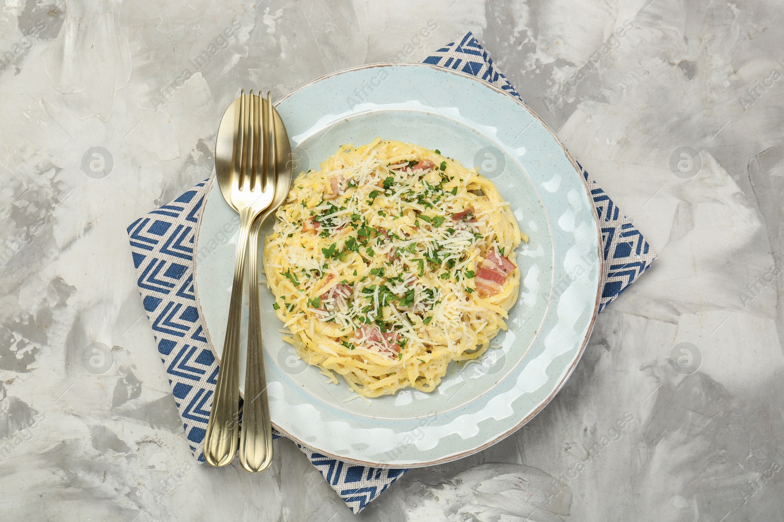 Photo of Delicious pasta Carbonara with bacon served on gray textured table, flat lay