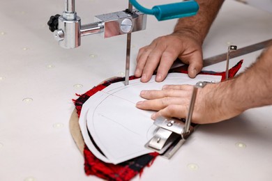 Photo of Man working at white table in professional workshop, closeup