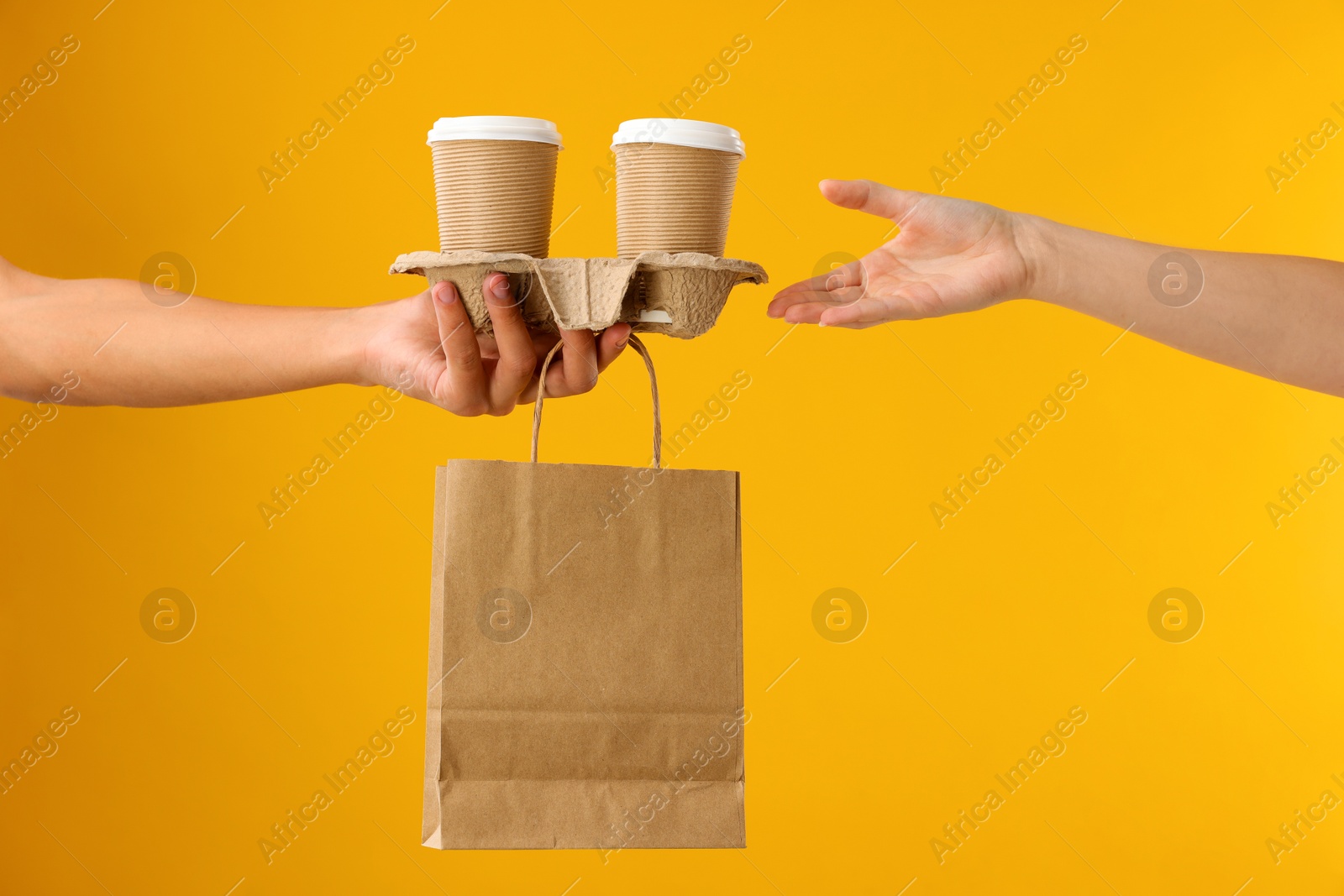 Photo of Fast-food worker giving customer's order on orange background, closeup