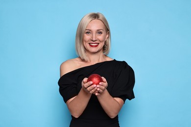 Photo of Smiling woman with Christmas bauble on light blue background