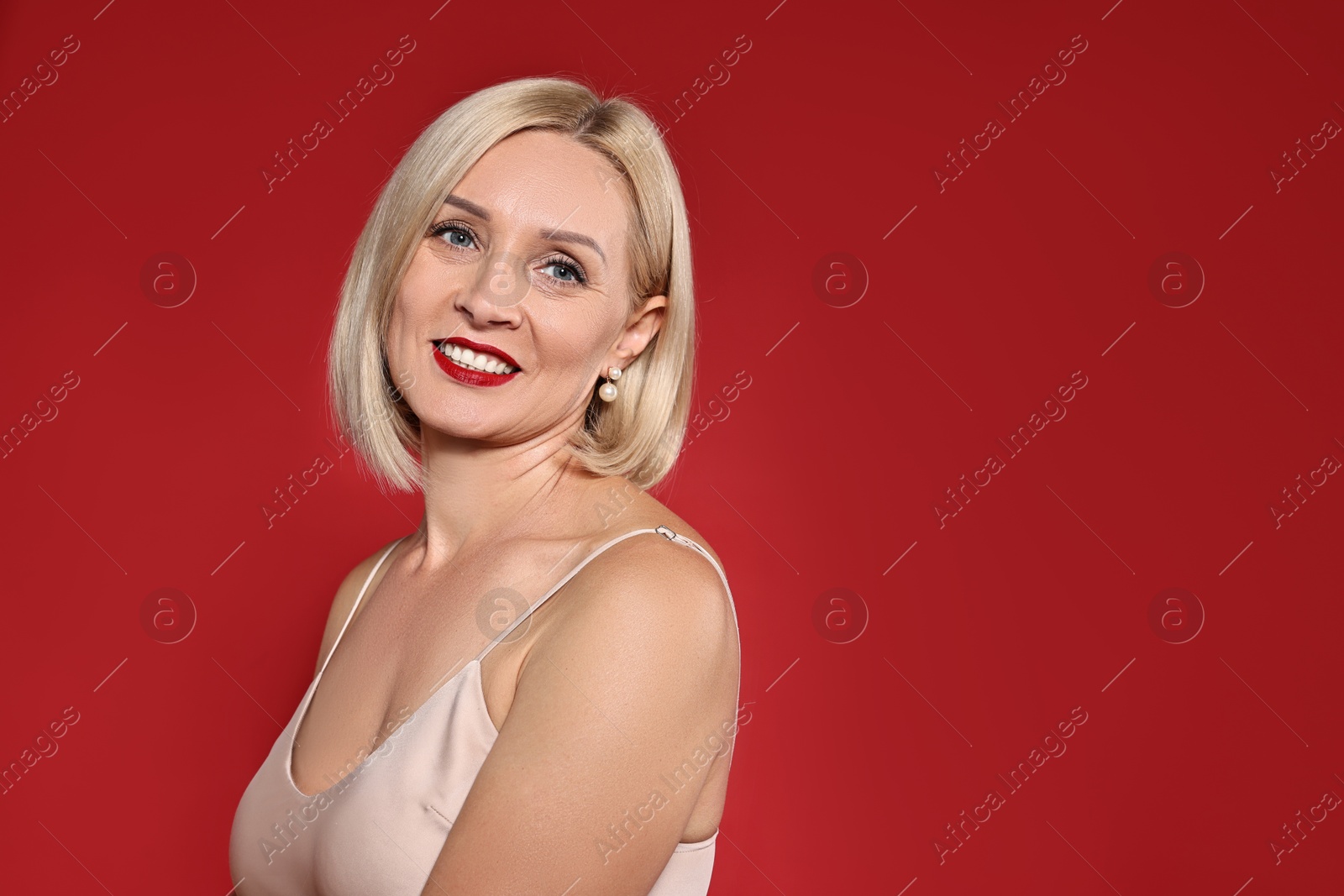 Photo of Smiling woman with perfect makeup on red background. Space for text