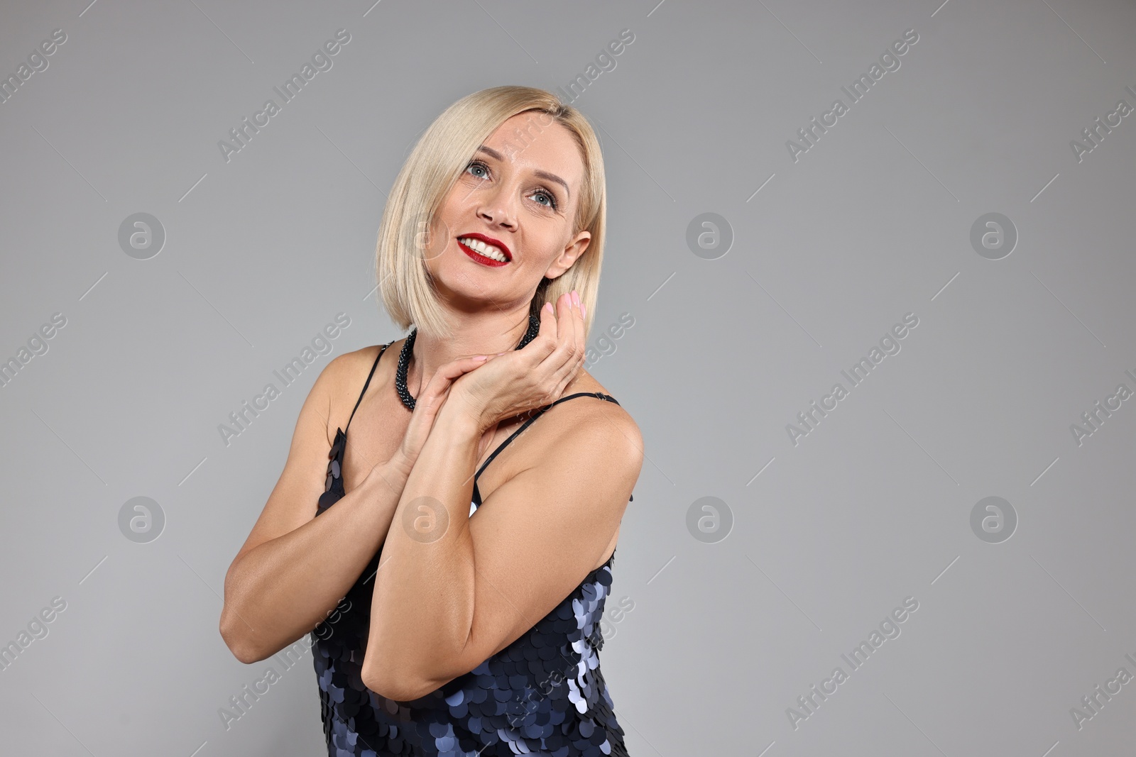 Photo of Smiling woman with perfect makeup on grey background. Space for text