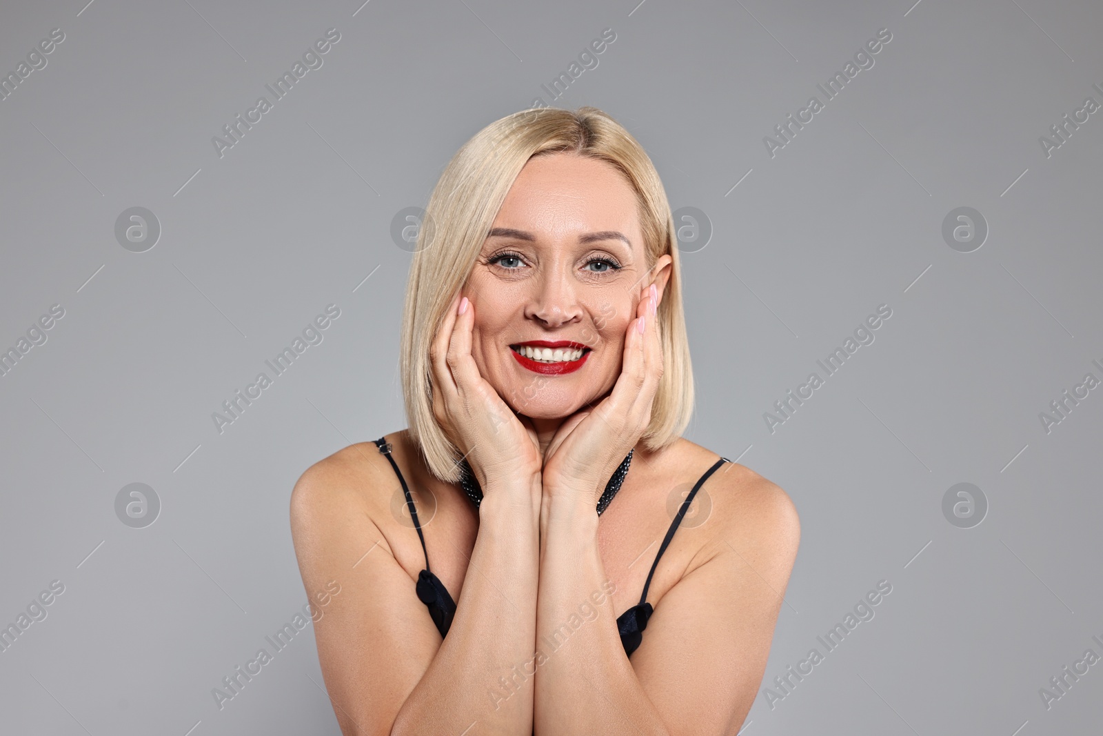 Photo of Smiling woman with perfect makeup on grey background