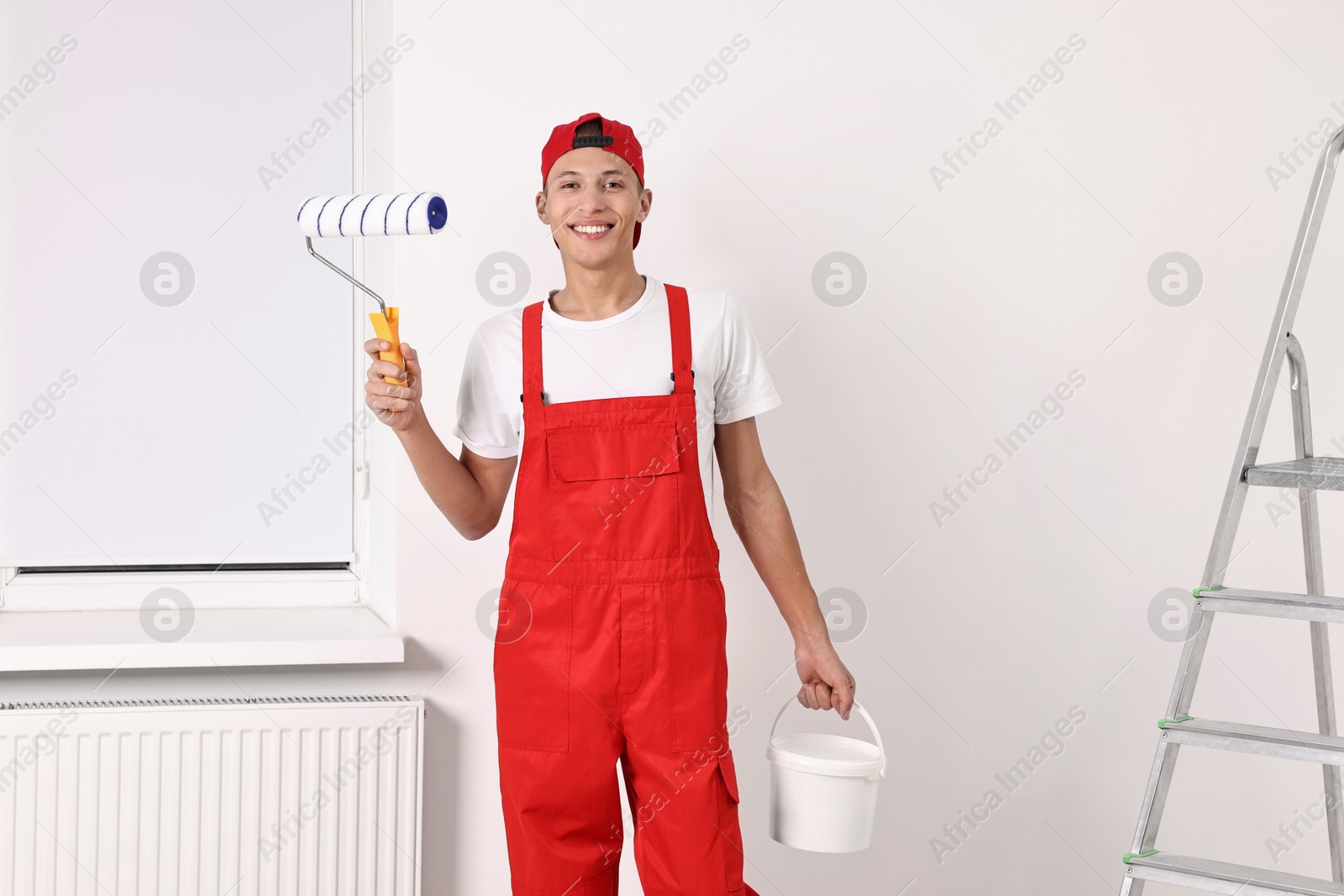 Photo of Smiling handyman with roller and paint indoors