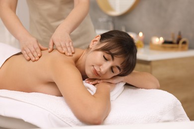 Young woman receiving back massage in spa salon