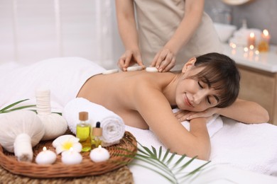 Photo of Young woman receiving hot stone massage in spa salon