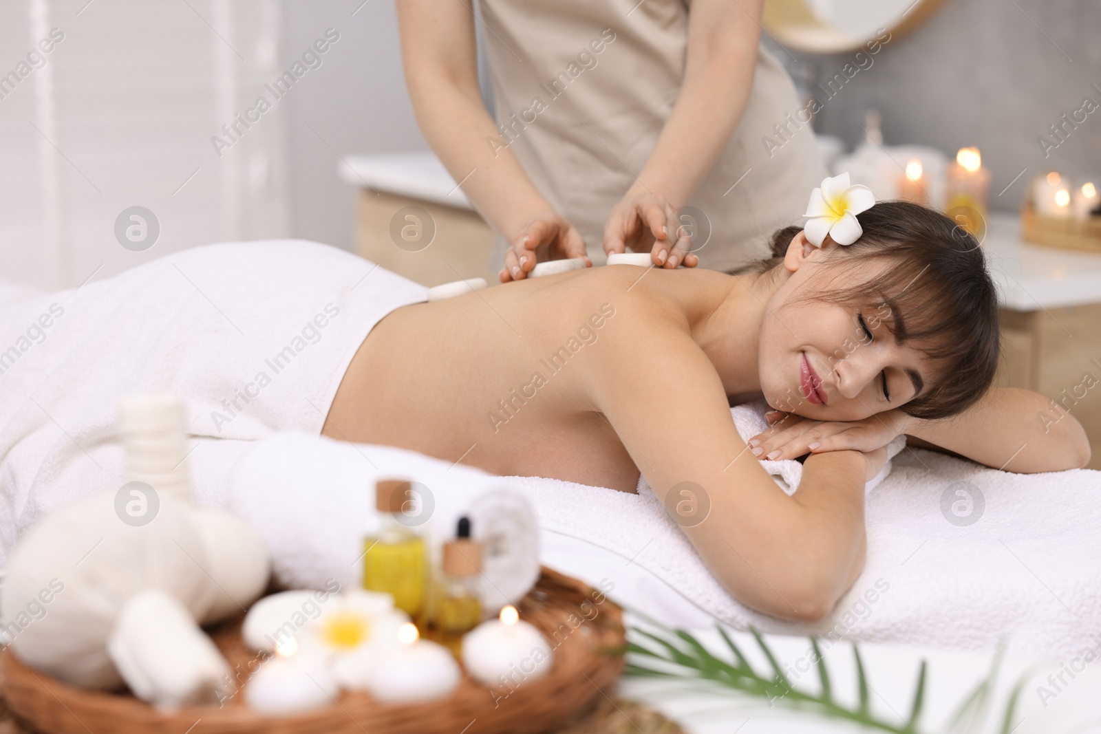 Photo of Young woman receiving hot stone massage in spa salon