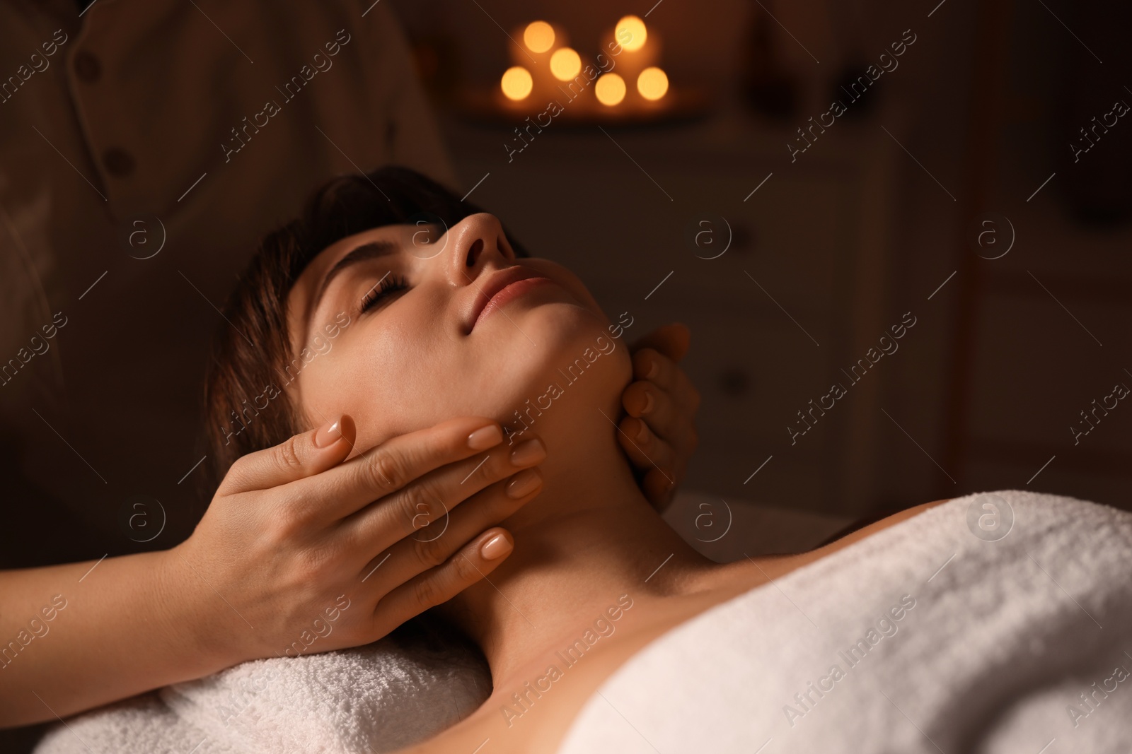 Photo of Young woman receiving face massage in spa salon