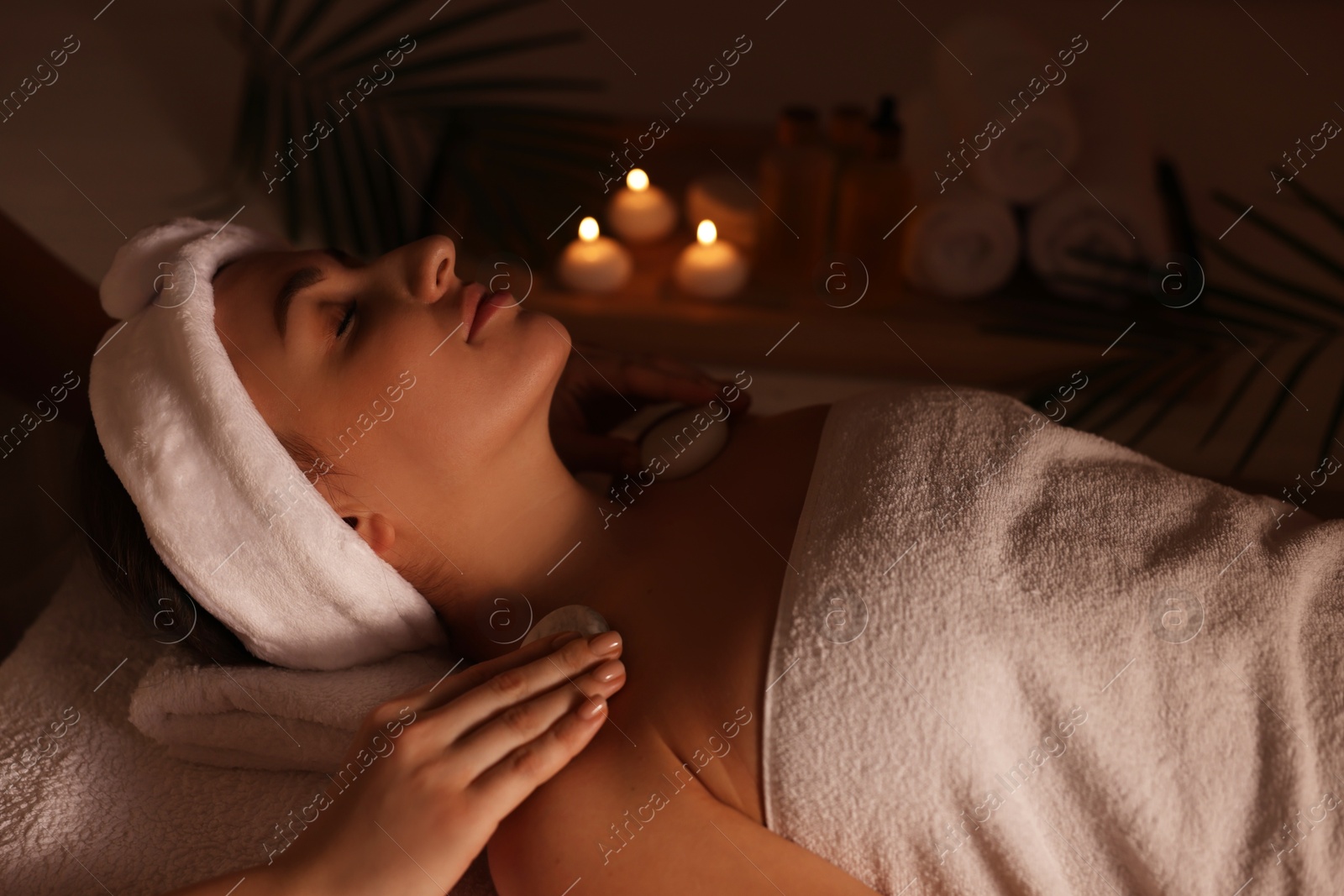 Photo of Young woman receiving hot stone massage in spa salon