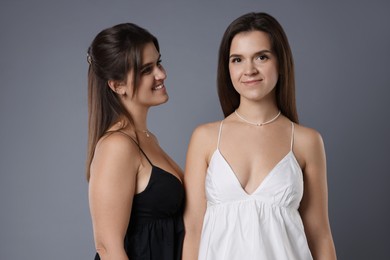 Photo of Portrait of beautiful twin sisters on grey background