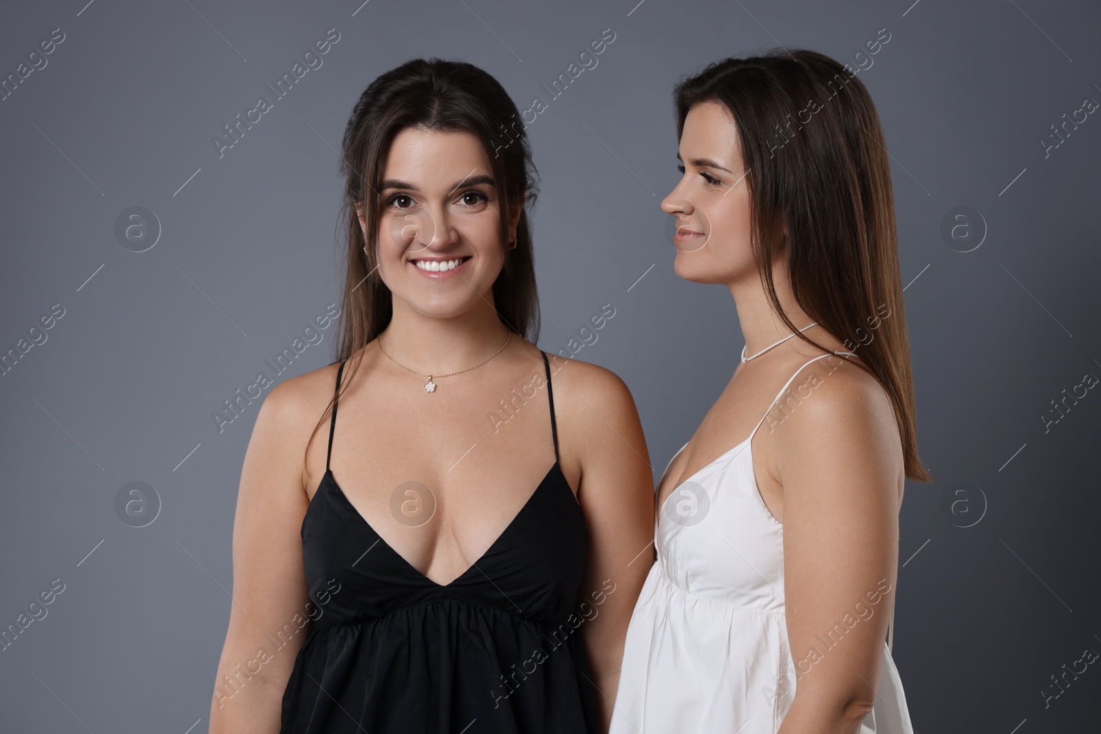 Photo of Portrait of beautiful twin sisters on grey background