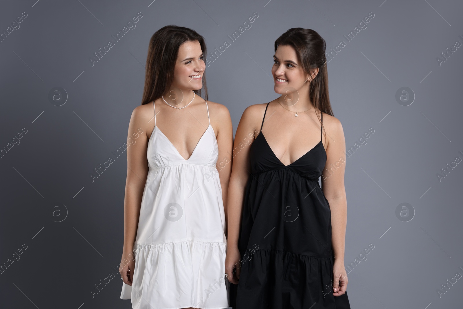 Photo of Portrait of beautiful twin sisters on grey background