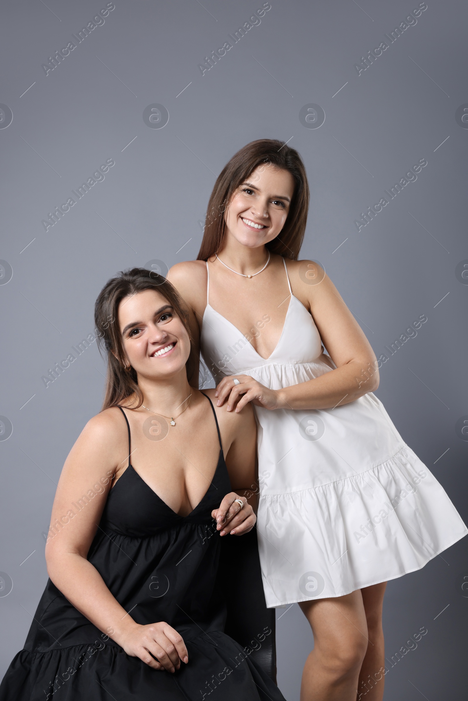 Photo of Portrait of beautiful twin sisters on grey background