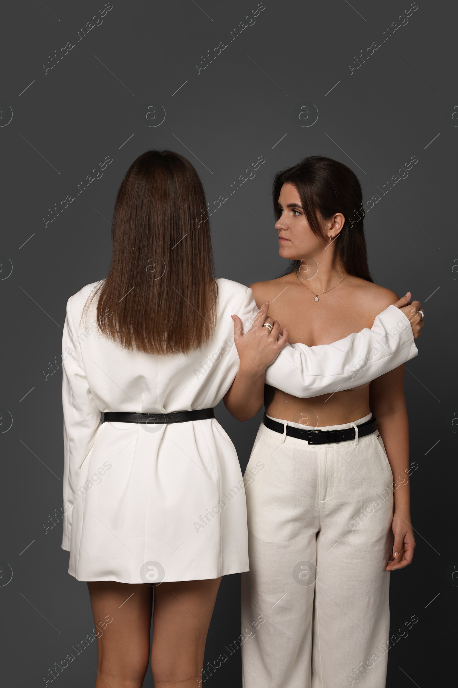 Photo of Portrait of beautiful twin sisters on grey background