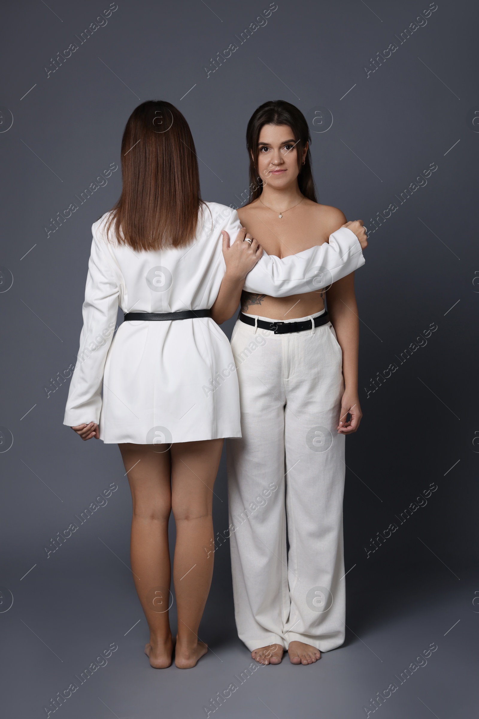 Photo of Portrait of beautiful twin sisters on grey background