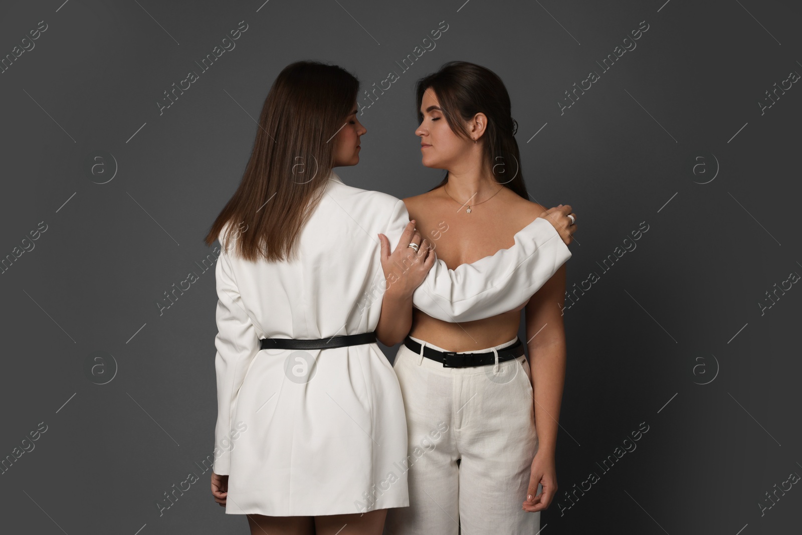 Photo of Portrait of beautiful twin sisters on grey background