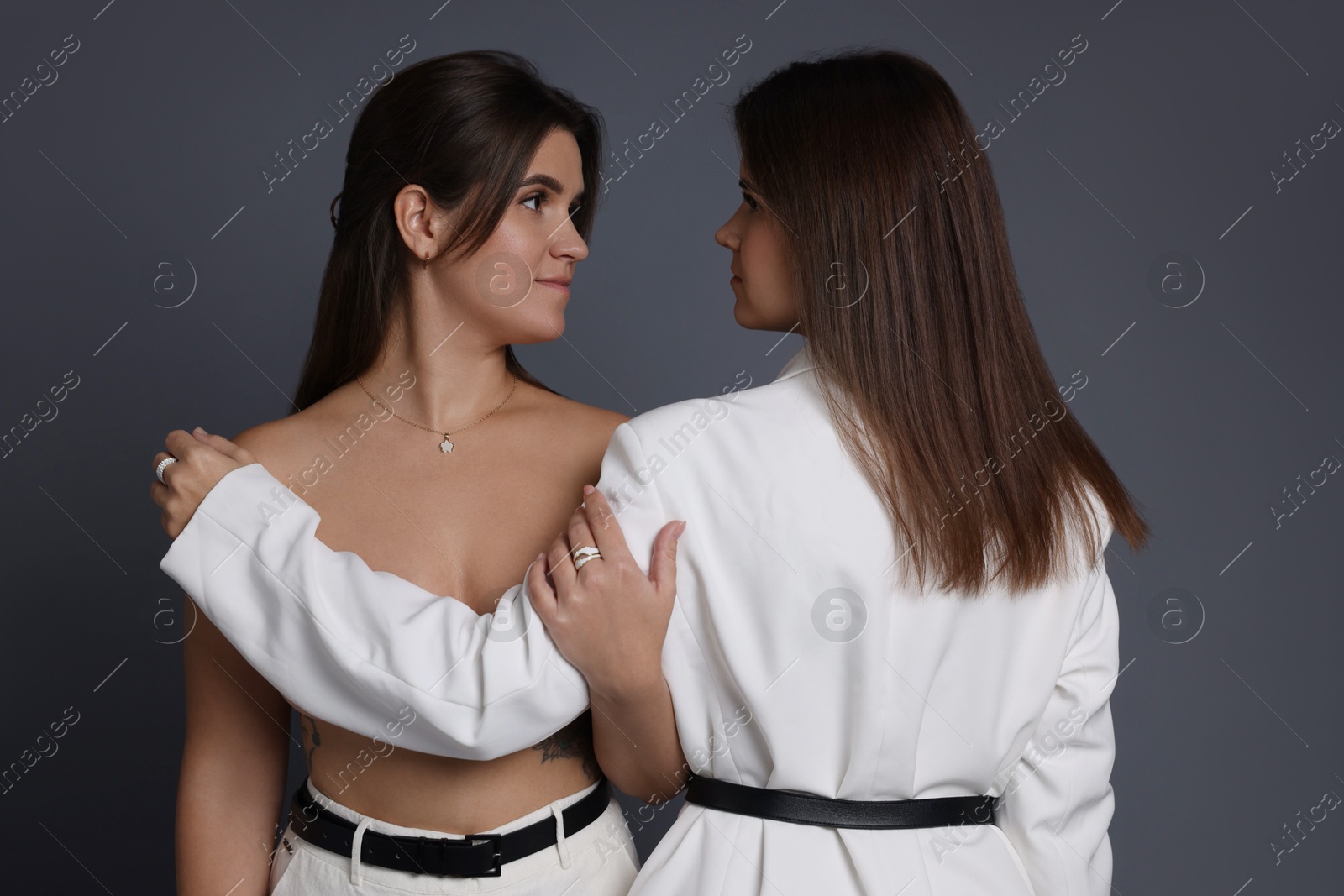 Photo of Portrait of beautiful twin sisters on grey background