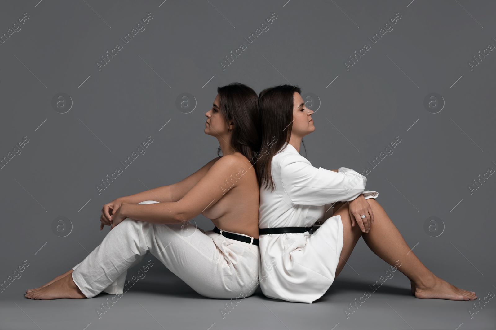 Photo of Portrait of beautiful twin sisters on grey background