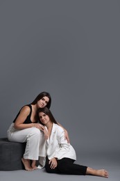 Photo of Portrait of beautiful twin sisters on grey background, space for text