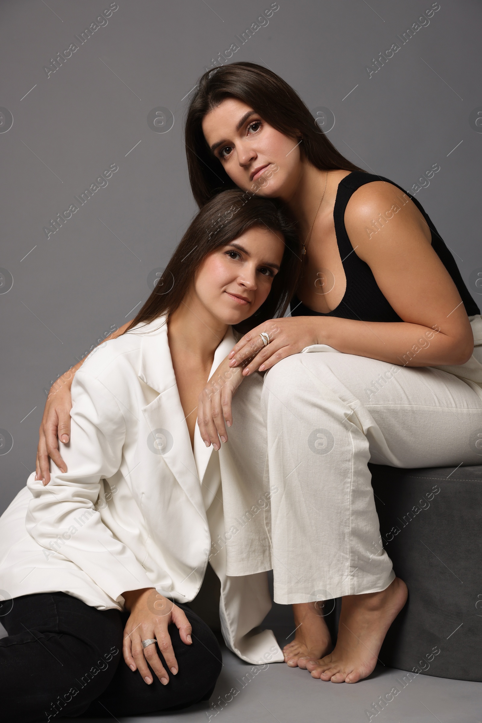 Photo of Portrait of beautiful twin sisters on grey background