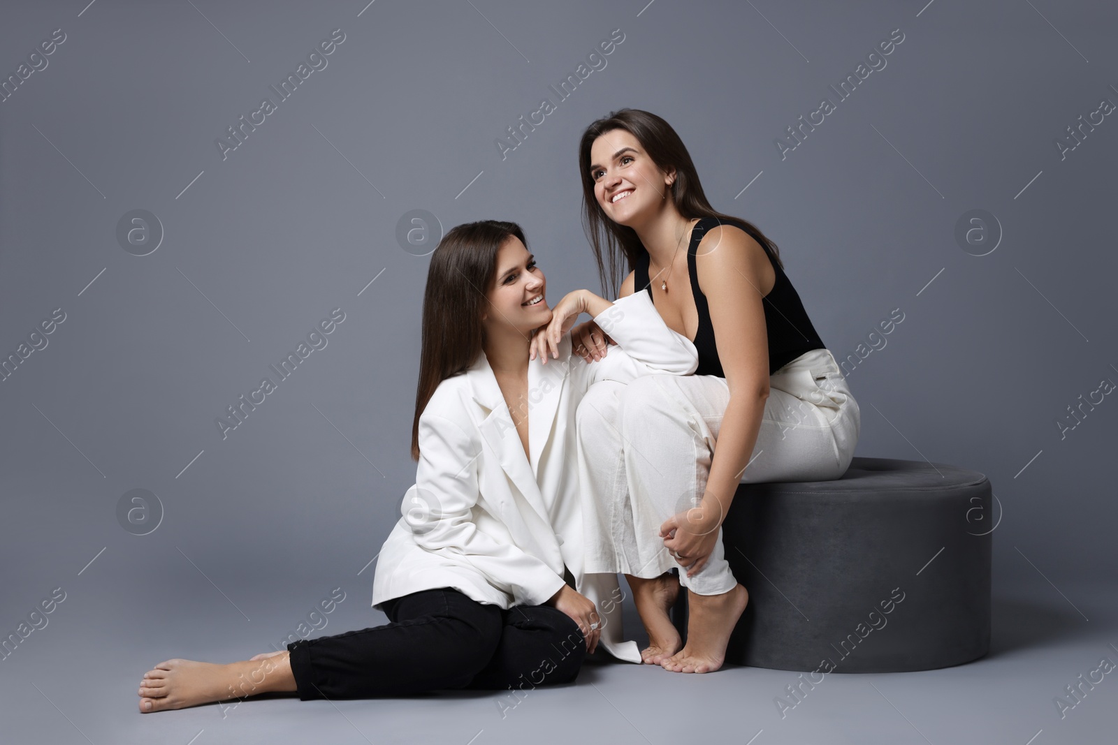 Photo of Portrait of beautiful twin sisters on grey background