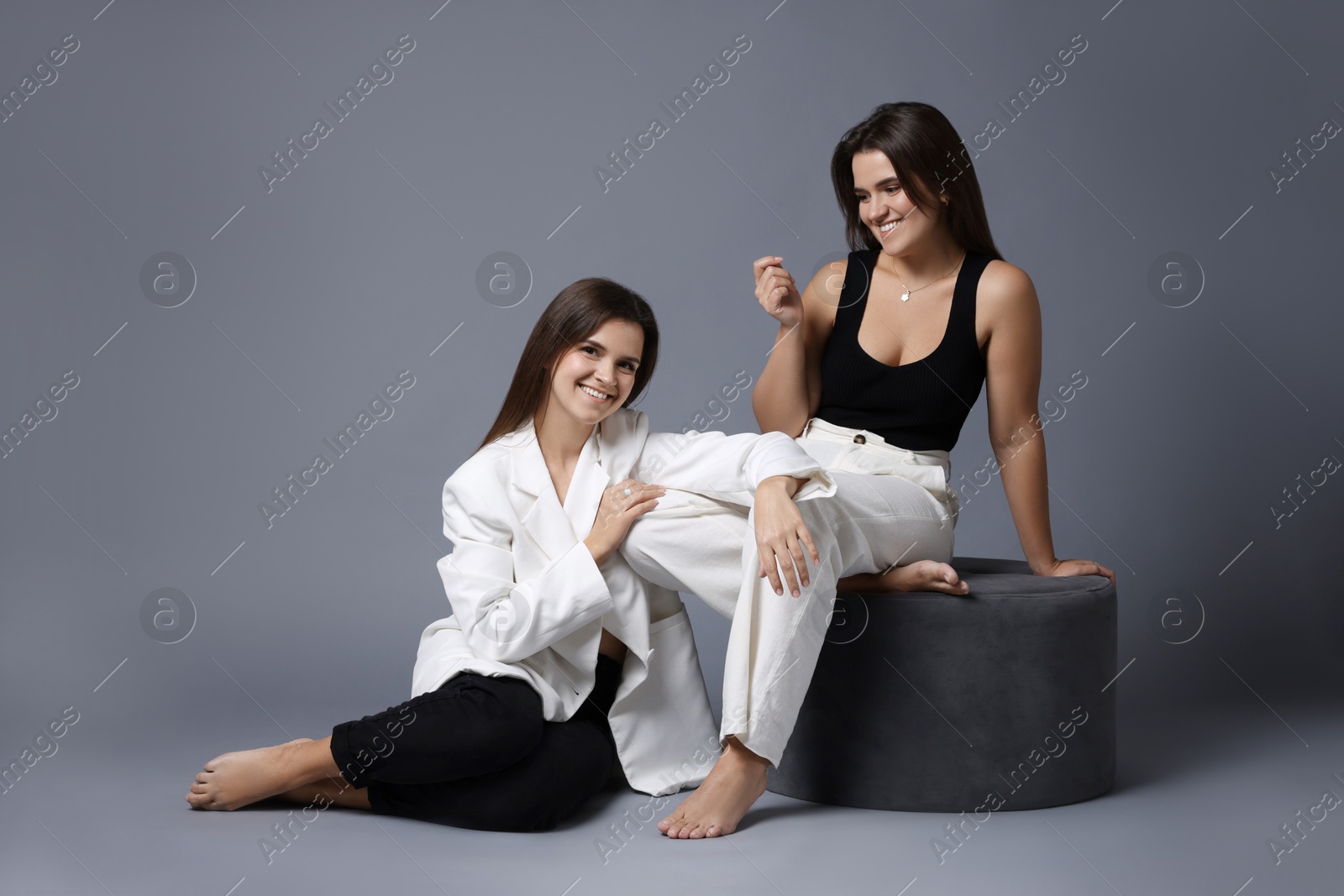 Photo of Portrait of beautiful twin sisters on grey background